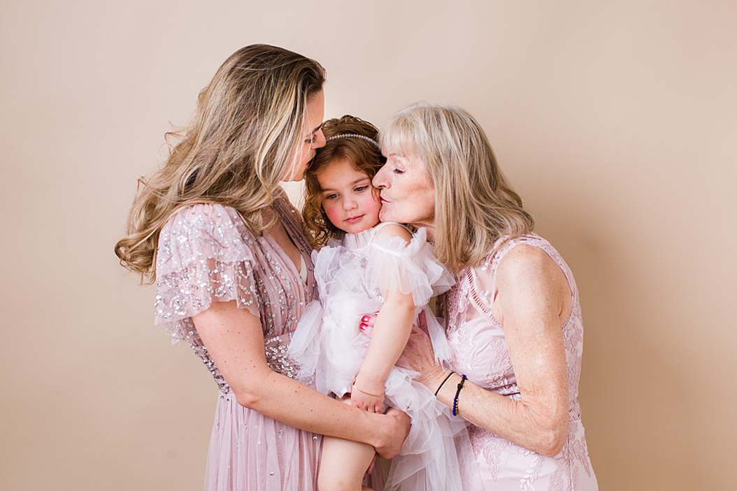 photoshoot-mother-daughter-grandmother-all-in-pink-beige-outfit-mother-and-grandmother-kissing-little-girl
