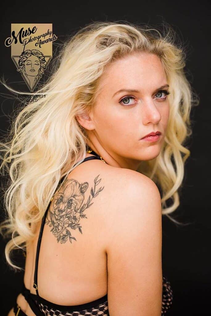 Muse Photography Awards gold-winning boudoir portrait, blonde woman with floral tattoo in black lingerie.