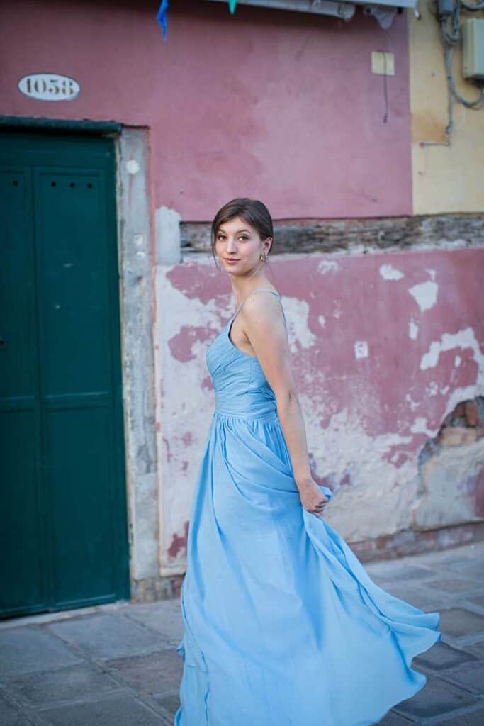 venice-romance-girl-in-front-of-pink-wall-green-door-in-blue-dress-looking-back-at-camera