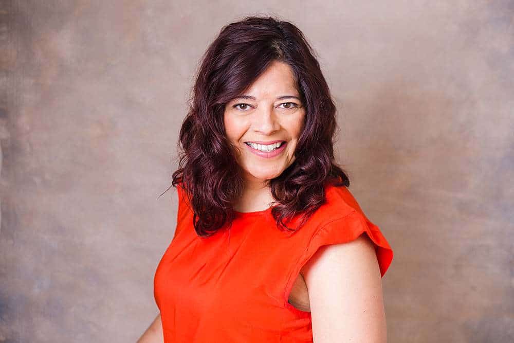 linkedin-photo-of-middle-age-woman-in-orange-top-smiling-in-front-of-pink-background-by-london-linkedin-headshot-phographer
